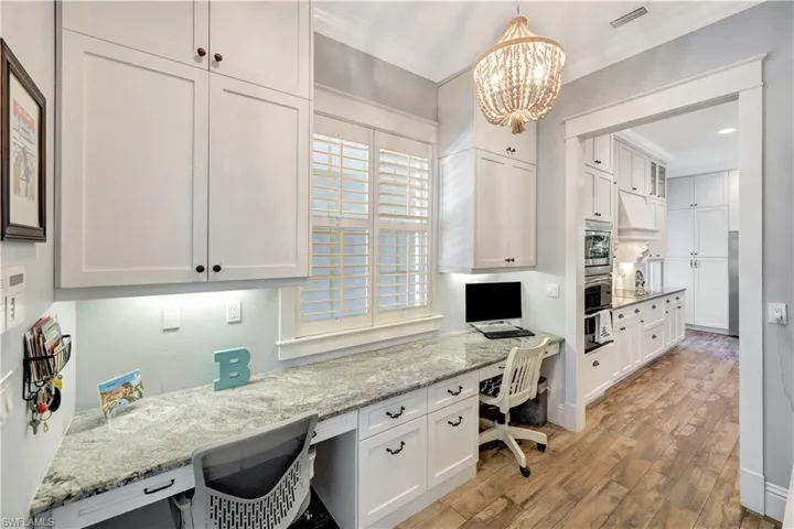 Office featuring built in study area, light wood-style flooring, a chandelier, and ornamental molding