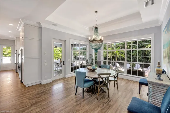 Dining room featuring ornamental molding, light wood-type flooring, a chandelier, and a raised ceiling