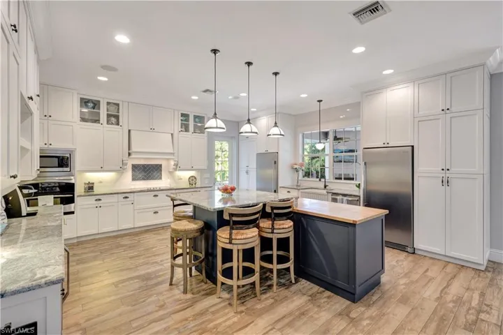 Kitchen featuring glass insert cabinets, built in appliances, white cabinetry, a center island, and recessed lighting