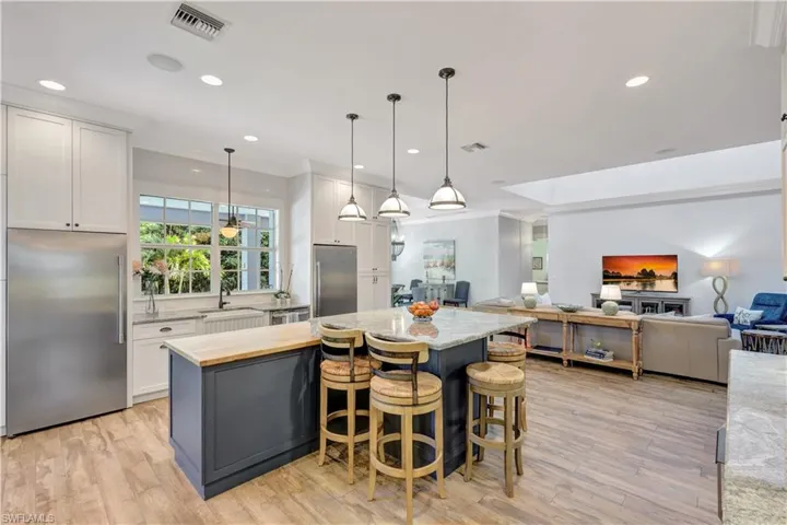 Kitchen featuring built in refrigerator, a breakfast bar area, open floor plan, decorative light fixtures, and a kitchen island