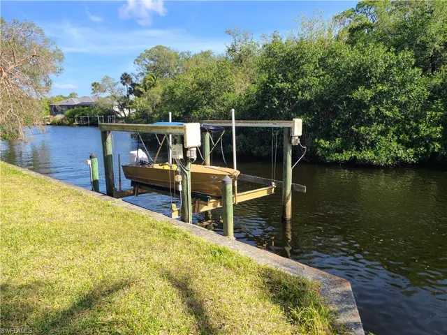 Dock area with a yard, boat lift, and a water view