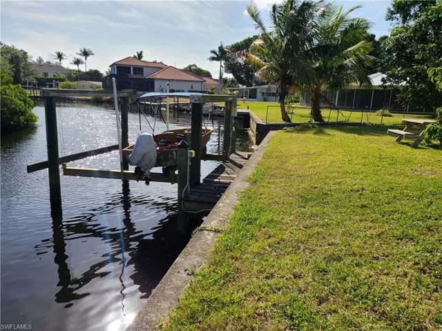 Dock area with a yard, boat lift, and a water view