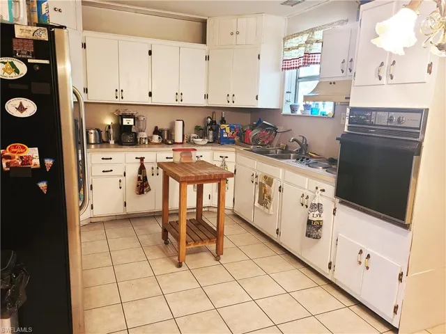 Kitchen with freestanding refrigerator, light countertops, oven, and white cabinetry