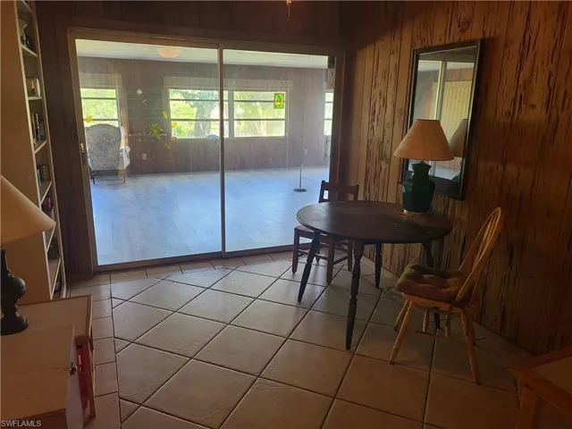 Dining area featuring a wealth of natural light, wooden walls, and light tile patterned floors