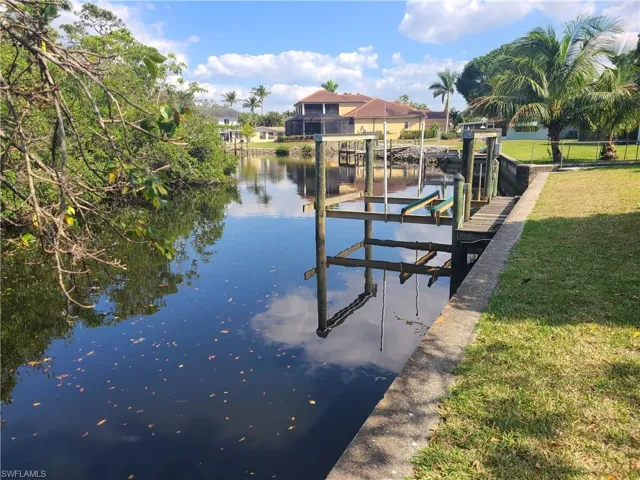 Boat lift featuring a lawn, a water view