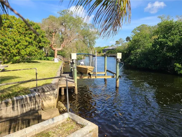 View of dock with a lawn, boat lift, and a water view