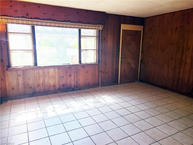 Spare room with light tile patterned floors, wood walls