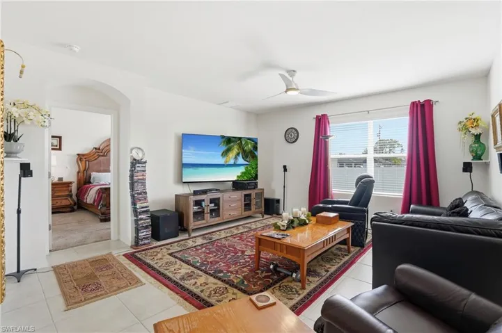Living area with light tile patterned floors, ceiling fan, and arched walkways