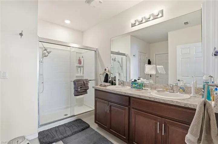 Full bath featuring double vanity, a shower stall, and light tile patterned floors