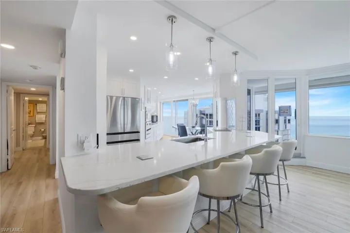 Kitchen with stainless steel refrigerator, a sink, light wood finished floors, white cabinetry, and recessed lighting