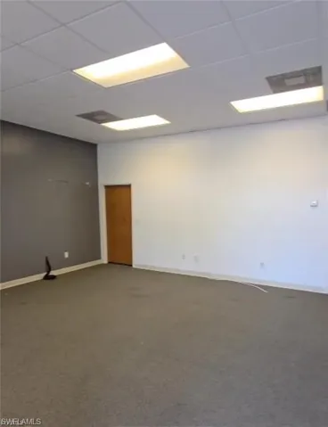 Empty room featuring a drop ceiling and carpet flooring
