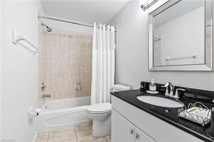 Full bath featuring shower / bathtub combination with curtain, vanity, and light tile patterned floors