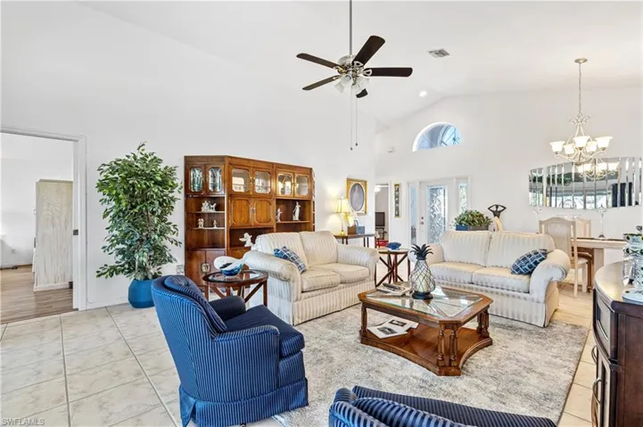 Living area featuring high vaulted ceiling, ceiling fan, a chandelier, and light tile patterned flooring