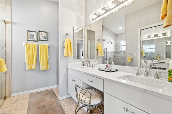 Full bath featuring a walk in shower, double vanity, and light tile patterned flooring