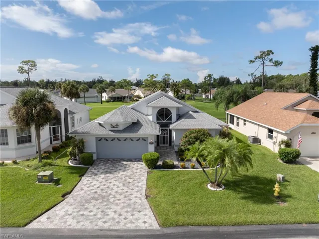 Single story home with a front lawn, a garage, stucco siding, a shingled roof, and decorative driveway