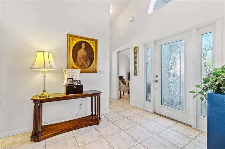 Foyer entrance with light tile patterned flooring and a towering ceiling