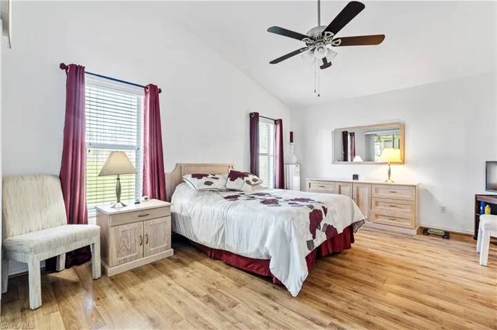 Bedroom with light wood-type flooring, multiple windows, ceiling fan, and high vaulted ceiling
