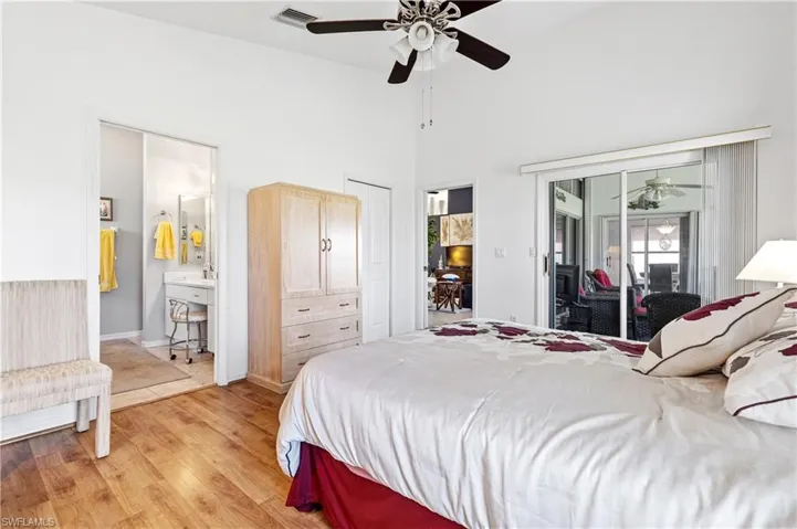 Bedroom with light wood finished floors, access to outside, ceiling fan, a towering ceiling, and ensuite bathroom