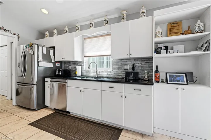 Kitchen with open shelves, white cabinets, backsplash, appliances with stainless steel finishes, and light tile patterned floors