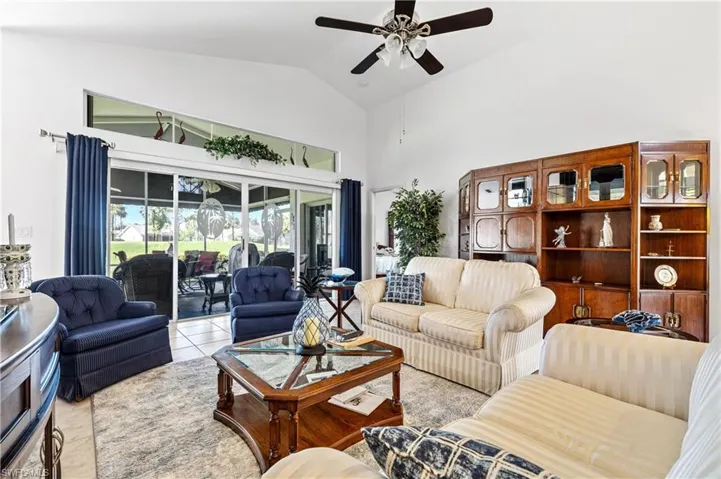 Living room with high vaulted ceiling, light tile patterned flooring, and a ceiling fan