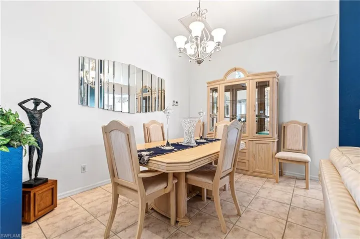 Dining room with a chandelier, light tile patterned floors, and lofted ceiling