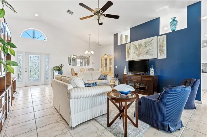 Living room with high vaulted ceiling, a chandelier, ceiling fan, light tile patterned flooring, and recessed lighting