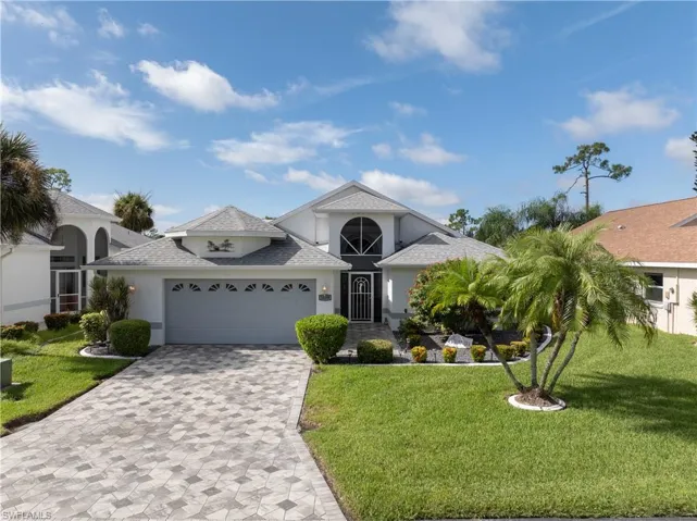 View of front of property featuring stucco siding, decorative driveway, roof with shingles, and a front yard
