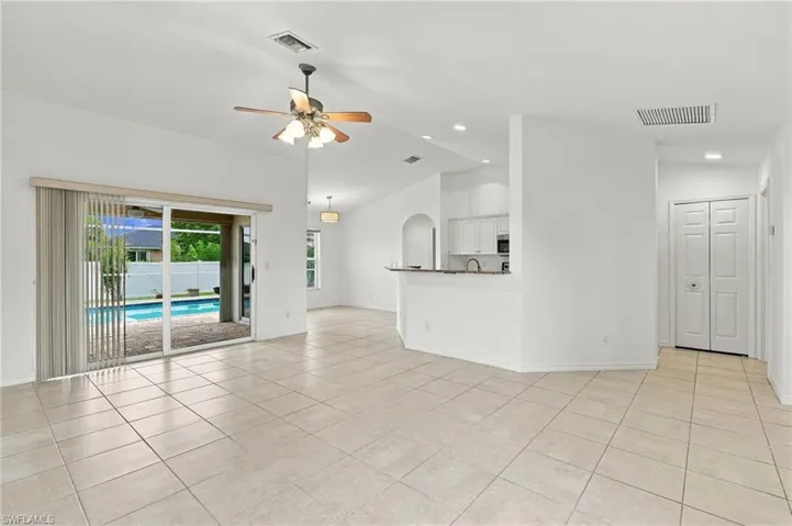 Spacious room with light-toned tile flooring, vaulted ceiling, and ceiling fan