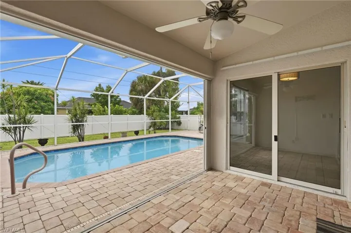 Screened-in patio with brick paver flooring, built-in swimming pool, and sliding glass door access to interior