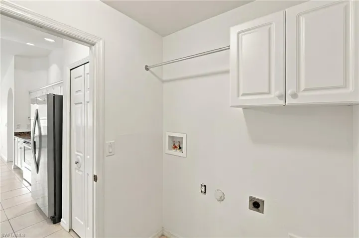White cabinetry with round knobs, laundry hookups, and a hanging rod