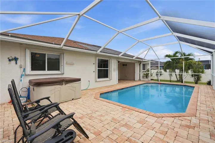 Screen-enclosed swimming pool with paver decking, integrated spa, and exterior access points