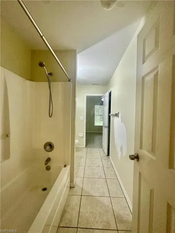 Bathroom featuring shower / bath combination, tile patterned flooring, toilet, and baseboards