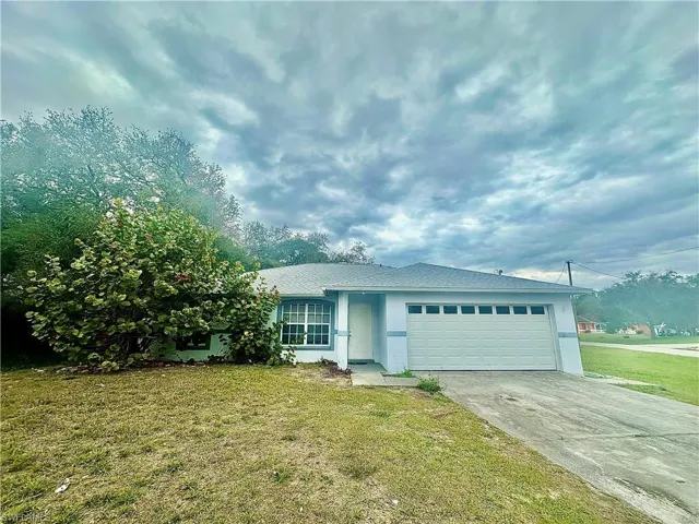 Ranch-style home with concrete driveway, stucco siding, an attached garage, and a front yard