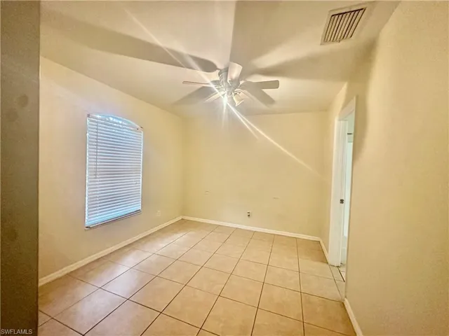 Spare room with ceiling fan, light tile patterned floors, visible vents, and baseboards