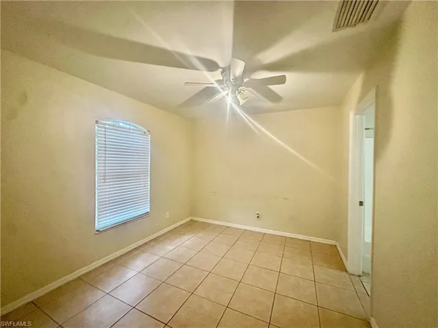 Spare room with light tile patterned floors, baseboards, visible vents, and a ceiling fan