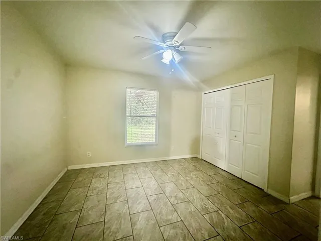 Unfurnished bedroom featuring a closet, a ceiling fan, and baseboards