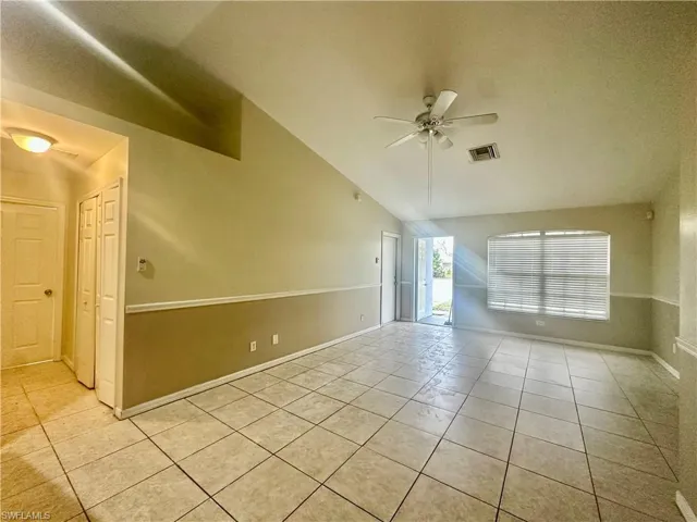 Unfurnished room featuring light tile patterned floors, ceiling fan, high vaulted ceiling, visible vents, and baseboards