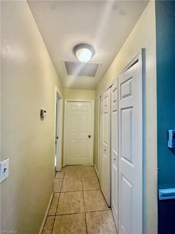 Hallway with light tile patterned flooring, visible vents, and baseboards