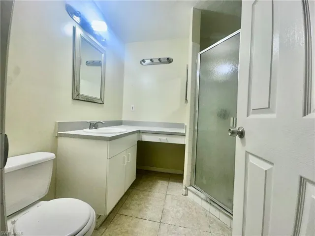 Full bathroom featuring a stall shower, tile patterned flooring, vanity, and toilet