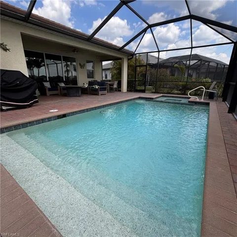 Combined pool / hot tub with a sunroom, glass enclosure, a patio area, and outdoor seating