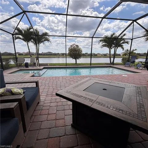 Swimming pool with a sunroom, a patio area, a water view, a lanai, and a jacuzzi