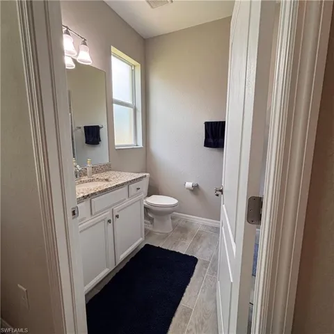 Half bathroom featuring vanity, a textured wall, and wood tiled floors