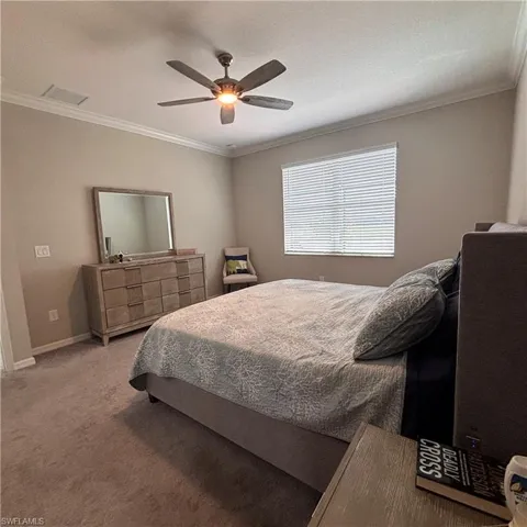 Carpeted bedroom featuring crown molding and a ceiling fan