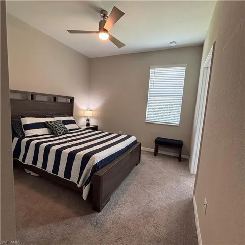 Bedroom with light carpet and a ceiling fan