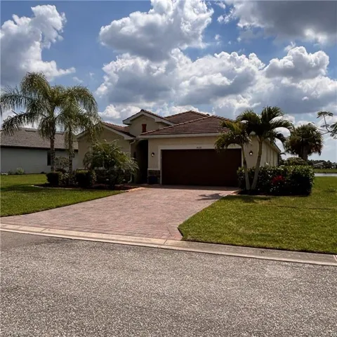 View of front of house featuring a front yard, an attached garage, decorative driveway, stucco siding, and a tiled roof
