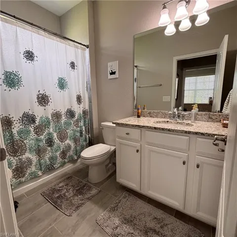 Full bath featuring vanity, hanging lights, and shower / bathtub combination with curtain