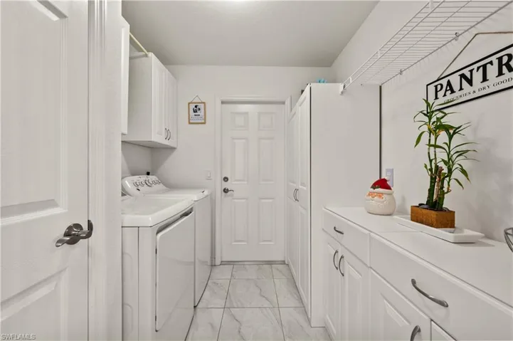 Laundry room with cabinet space, light marble finish flooring, and independent washer and dryer