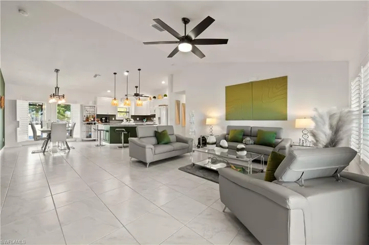 Living area with lofted ceiling, a ceiling fan, and light tile patterned floors