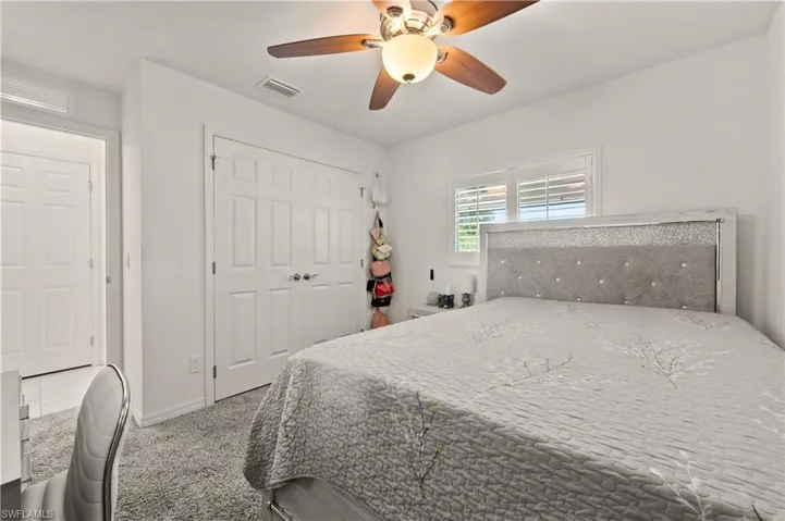 Bedroom featuring ceiling fan, light colored carpet, and a closet