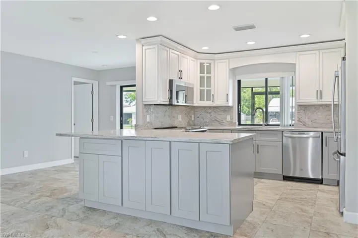 Central kitchen island with an extended countertop for seating, complemented by recessed lighting and light-toned cabinetry